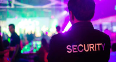 Security guard monitoring a nightclub environment with vibrant lighting in Vancouver.