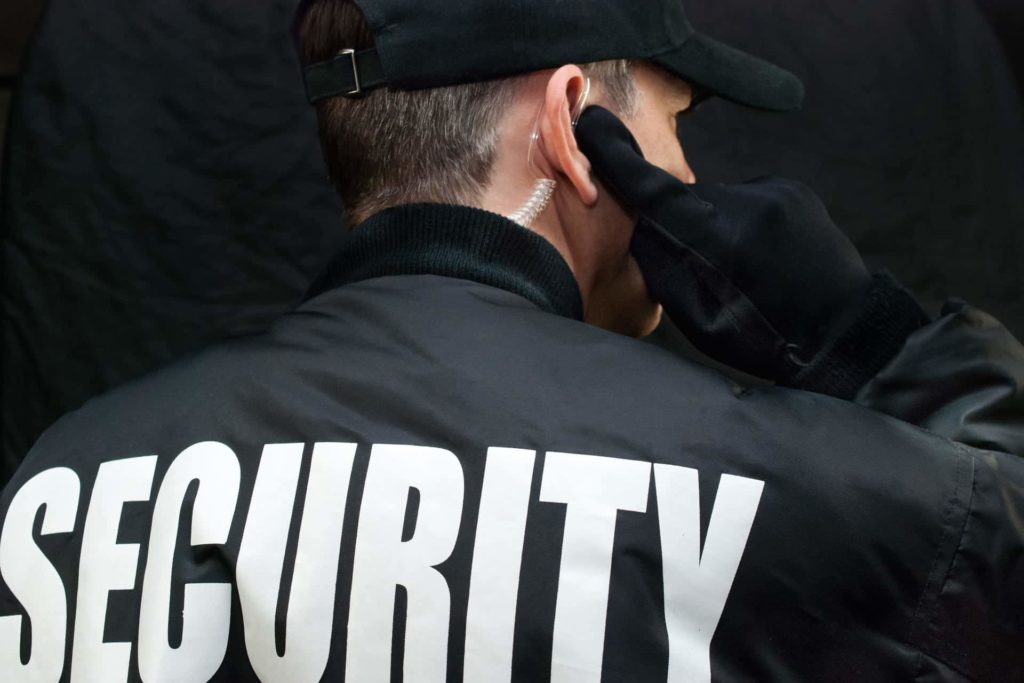 Back view of a security guard in uniform using a radio earpiece for communication during duty in Vancouver.