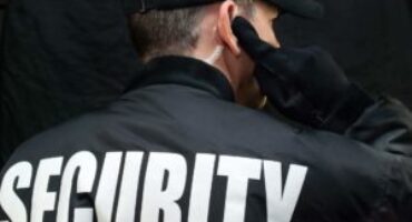 Back view of a security guard in uniform using a radio earpiece for communication during duty in Vancouver.
