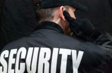 Back view of a security guard in uniform using a radio earpiece for communication during duty in Vancouver.