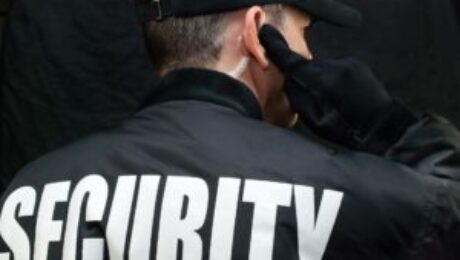 Back view of a security guard in uniform using a radio earpiece for communication during duty in Vancouver.