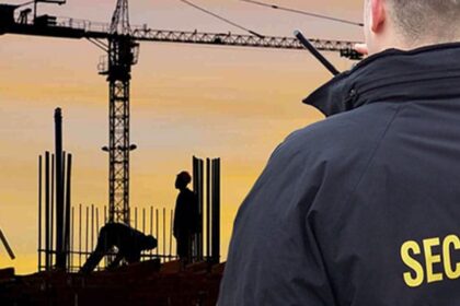 Security guard overseeing workers at a construction site during sunset, ensuring safety and protection in Vancouver.