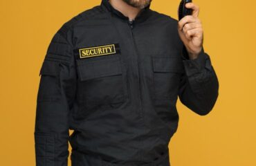 Security guard monitoring surveillance cameras on multiple screens, representing the combination of human and electronic security