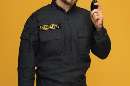 Security guard monitoring surveillance cameras on multiple screens, representing the combination of human and electronic security