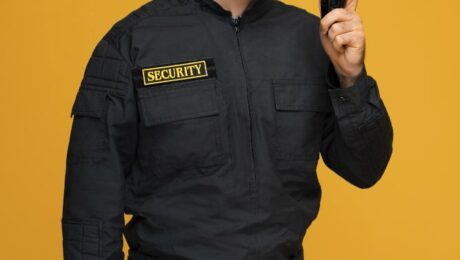 Security guard monitoring surveillance cameras on multiple screens, representing the combination of human and electronic security